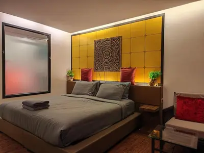 a bedroom with a large bed with a yellow wall at 7 Floor - Pool view Studio room at TBHR near Kata beach in Kata Beach