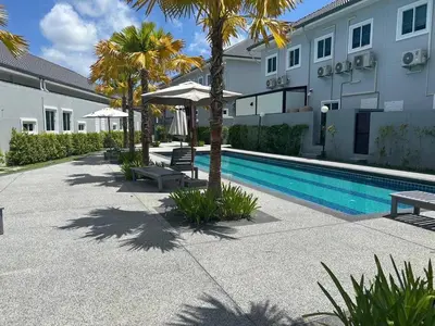 a swimming pool next to a building with palm trees at The Rich Villas Palai in Chalong