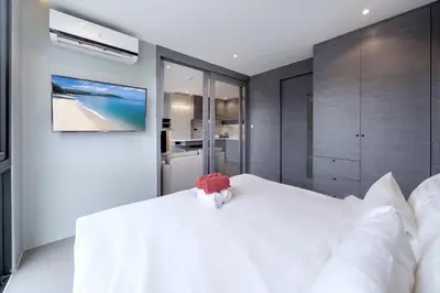a bedroom with a white bed with a teddy bear on it at Tropics Kamala Hill View Suite CTG L708, Best Amenities near Kamala beach in Kamala Beach