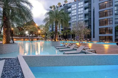 a pool with lounge chairs and palm trees and buildings at Tropics Kamala Hill View Suite CTG L708, Best Amenities near Kamala beach in Kamala Beach