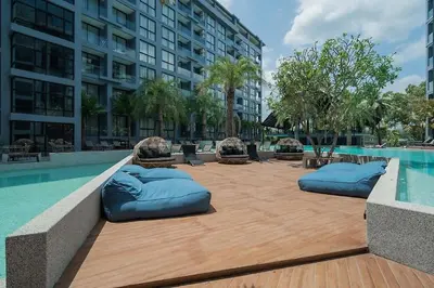a swimming pool with blue pillows on a wooden deck at Tropics Kamala Hill View Suite CTG L708, Best Amenities near Kamala beach in Kamala Beach