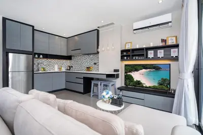 a living room with a white couch and a tv at Tropics Kamala Hill View Studio CTG P613 near Beach and Fantasea in Kamala Beach