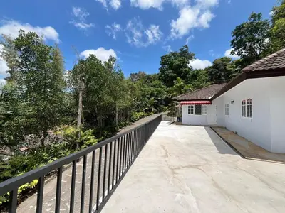 a fence next to a white building with trees at Prime Hill Kathu Phuket D3 in Ban Ket Ho