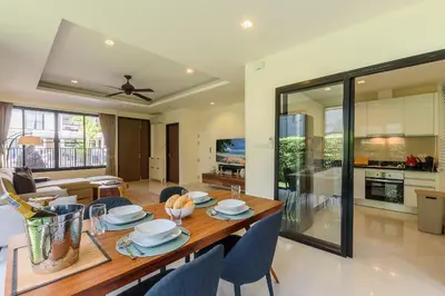 a dining room and living room with a table and chairs at Laguna Park Townhouse by Villacarte in Laguna Phuket