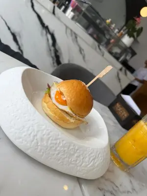 a sandwich on a plate on a table with a drink at The little Mermaid in Patong Beach