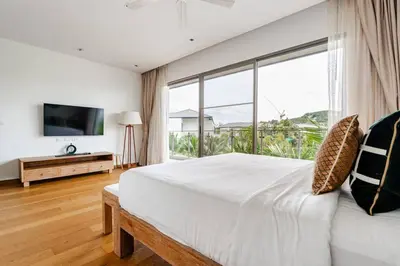 a bedroom with a large bed and a large window at WEG Laguna Residence in Thalang