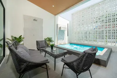 a swimming pool in a living room with chairs and a table at 6BR Patong pool villa in Patong Beach