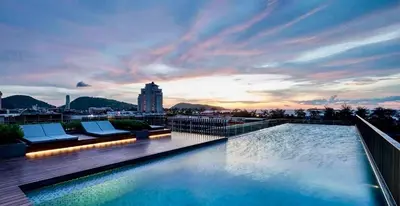 a swimming pool on the roof of a building with a sunset at Patong luxurious Vacation one bedroom Apt The deck in Patong Beach