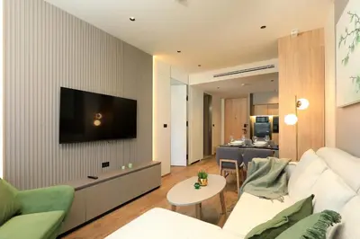 a living room with a couch and a tv on a wall at 1bdr New Apartment near Layan Beach in Ko Kala