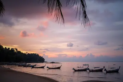 a group of boats sitting on the beach at sunset at 1bdr New Apartment near Layan Beach in Ko Kala