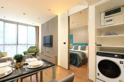 a living room and bedroom with a bed and a table and a washing machine at 1bdr New Apartment near Layan Beach in Ko Kala