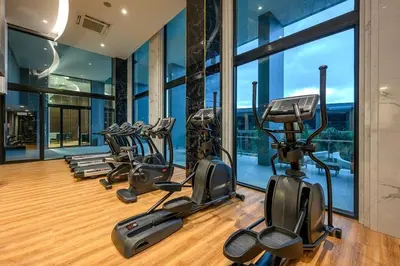 a gym with several cardio machines in a room with windows at Surin Mida Grande residence with jacuzzi and sea view - Bang Tao & Surin beach in Surin Beach