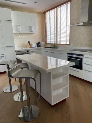a kitchen with white cabinets and a island with bar stools at Beachfront in Surin Beach