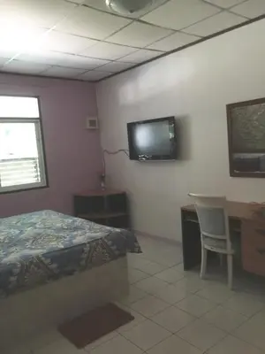 a bedroom with a bed and a desk and a tv on the wall at Nan Inn Bungalow in Karon Beach