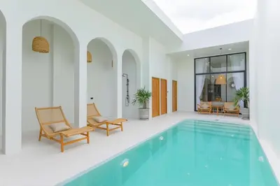 a swimming pool in a house with two chairs at Balina Private Pool Villa in Ban Chin Tham Mai