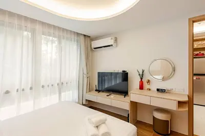 a bedroom with a bed and a tv and a mirror at Fantasea Kamala Walk to Beach Pool & Gym Modern 1BR in Kamala Beach
