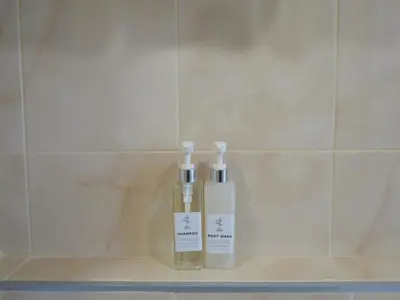 two bottles ofodorizers sitting on a shelf in a bathroom at The Village Poshtel in Ban Khlong Haeng