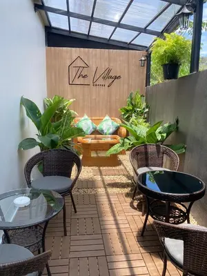a patio with tables and chairs and a sign that reads the village at The Village Poshtel in Ban Khlong Haeng