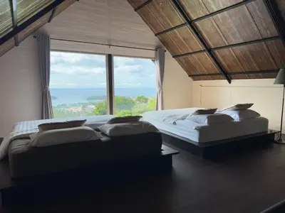 a large bedroom with two beds and a large window at Choncharm house 2 in Kata Beach