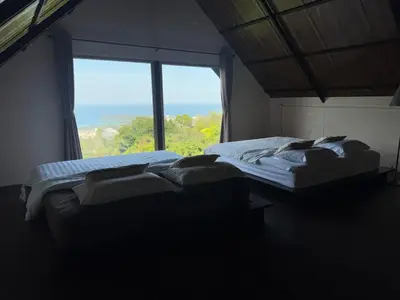 two beds in a room with a large window at Choncharm house 2 in Kata Beach