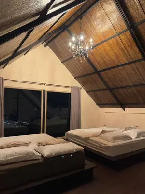 two beds in a room with a chandelier at Choncharm house 2 in Kata Beach