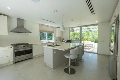 a kitchen with a island with a stove and chairs at Top Pool Villa Layan Estate Laguna Bangtao in Layan Beach