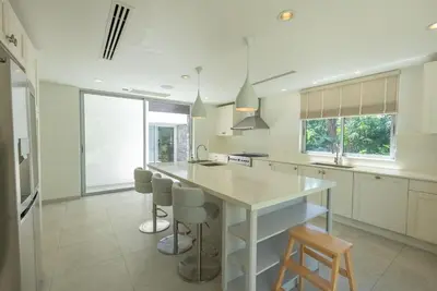a kitchen with a large white island with bar stools at Top Pool Villa Layan Estate Laguna Bangtao in Layan Beach
