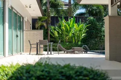 a patio with two chairs and a table and benches at Coconut villa Phuket in Laguna Phuket