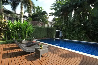 a backyard with a swimming pool and a wooden deck at Coconut villa Phuket in Laguna Phuket