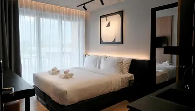 a hotel room with a bed and a window at Lush inn Phuket in Ban Suan