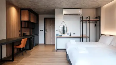 a bedroom with a large white bed and a kitchen at Lush inn Phuket in Ban Suan