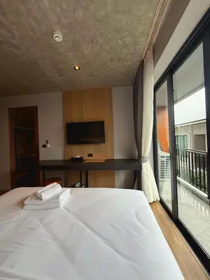 a bedroom with a bed and a large window at Lush inn Phuket in Ban Suan