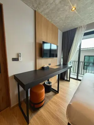 a desk in a room with a bed and a tv at Lush inn Phuket in Ban Suan