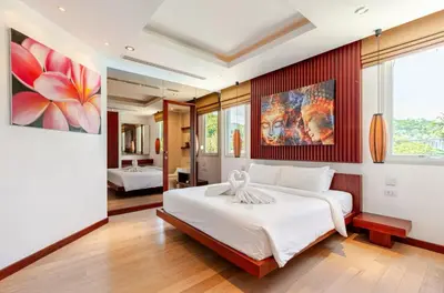 a bedroom with a large bed and a painting on the wall at Luxuriously private seafront Bangtao beach in Surin Beach