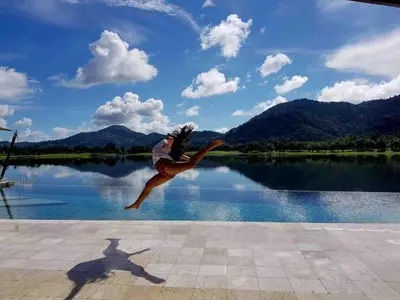 a person jumping in the air near a body of water at Tranquil lake view villa on Phuket golf estate in Kathu
