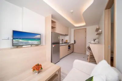 a living room with a kitchen and a television on a wall at \u5168\u65b0\u73b0\u4ee3\u98ce\u683c \u9b45\u529b\u6cf3\u6c60\u516c\u5bd3 in Kamala Beach