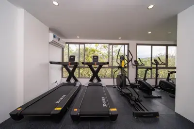 a gym with treadmills and a row of exercise bikes at \u5168\u65b0\u73b0\u4ee3\u98ce\u683c \u9b45\u529b\u6cf3\u6c60\u516c\u5bd3 in Kamala Beach
