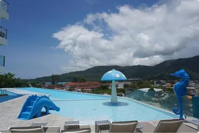 a swimming pool with a blue umbrella and chairs at Studio Sea view with kitchen by Renttini in Kamala Beach