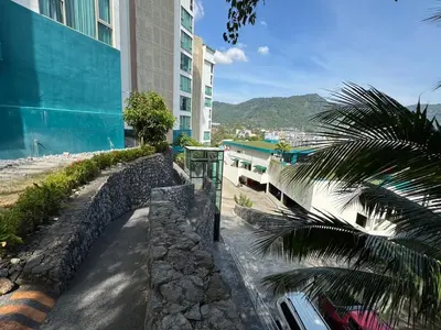 a bus stop next to a building with a palm tree at Studio Sea view with kitchen by Renttini in Kamala Beach