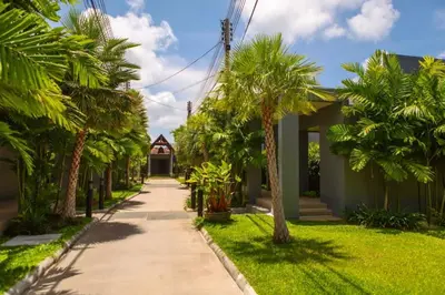 a sidewalk lined with palm trees in front of a house at VILLA Emere Private Pool Nai Harn beach in Nai Harn Beach