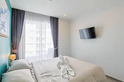 a bedroom with a bed with a tv on the wall at Pool View 1 Bed Apt T2-520 in Chalong