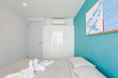 a white bed in a room with a blue wall at Pool View 1 Bed Apt T2-520 in Chalong