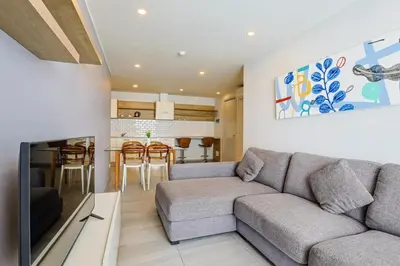 a living room with a couch and a kitchen at Pool View 1 Bed Apt T2-520 in Chalong