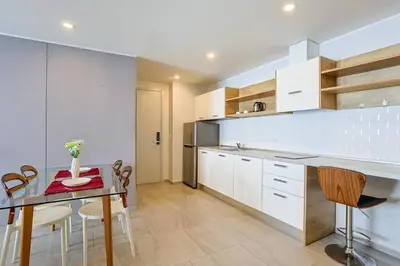a kitchen with white cabinets and a table and chairs at Pool View 1 Bed Apt T2-520 in Chalong