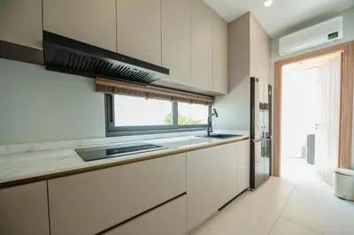 a kitchen with white cabinets and a window at Mouana Breeze Mai Khao 5-bedroom Pool Villa 9914 in Mai Khao Beach