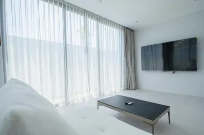 a living room with a coffee table in front of a large window at Mouana Breeze Mai Khao 5-bedroom Pool Villa 9914 in Mai Khao Beach
