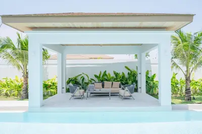 a white patio with a couch and chairs at Mouana Breeze Mai Khao 5-bedroom Pool Villa 9914 in Mai Khao Beach