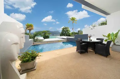 a patio with a table and chairs next to a swimming pool at Atika Villas xero oceanfront pool villa in Patong Beach