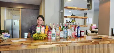 a woman standing behind a bar with bottles of alcohol at KT8 Hotel AoNang in Ban Khlong Haeng