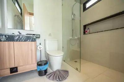 a bathroom with a toilet and a glass shower at Mouana Breeze Mai Khao VIP 4-bedroom Pool Villa 9913 in Mai Khao Beach